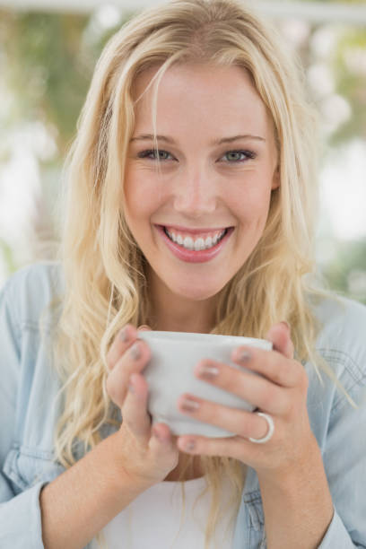 istock Pretty blonde sitting at table having coffee smiling at camera 692661288