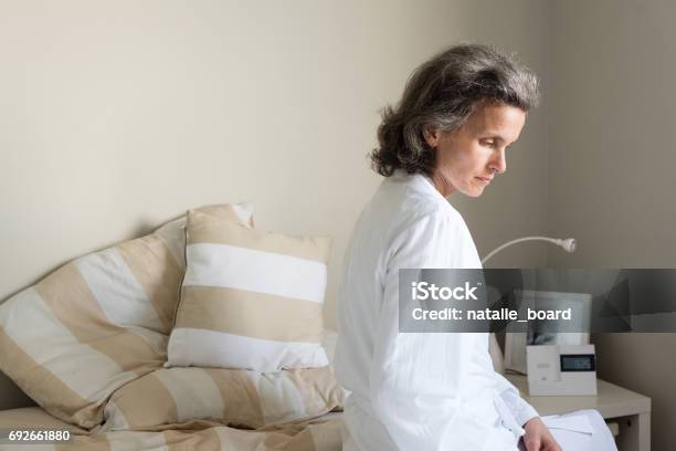 Photo libre de droit de Femme Assise Sur Le Lit Dâge Moyen banque d'images et plus d'images libres de droit de Ménopause - Ménopause, Femmes d'âge mûr, Assis