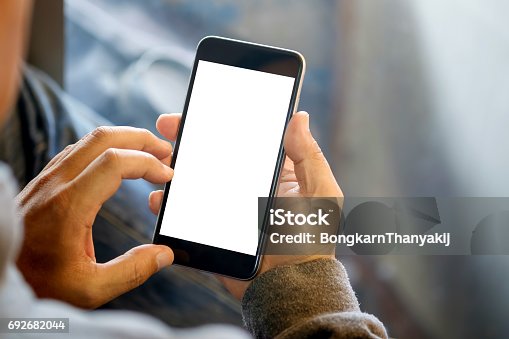 istock Man holding smart phone with blurred background. 692682044