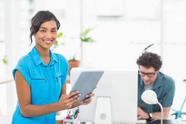 istock Smiling businesswoman using tablet with colleagues behind 692687424