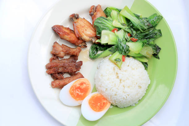 stir fried vegetables, Hard-boiled egg, Fried pork and Fried chicken wings with thai jasmine rice on dish. Thai food.