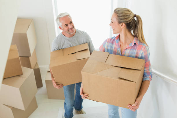 istock Happy couple carrying cardboard moving boxes 692720696