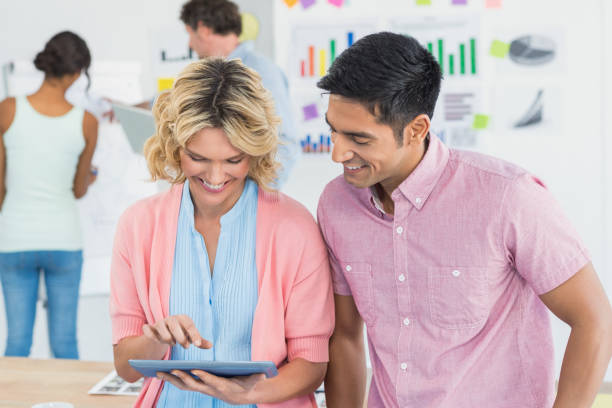 istock Casual businesspeople using digital tablet with colleagues behind in office 692721046