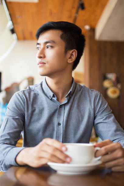 istock Serious Young Asian Man Sitting in Cafe 692732460