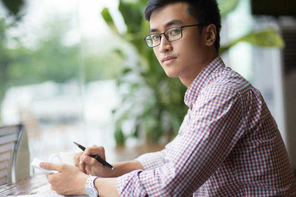 istock Serious young Asian student sitting at table 692732528