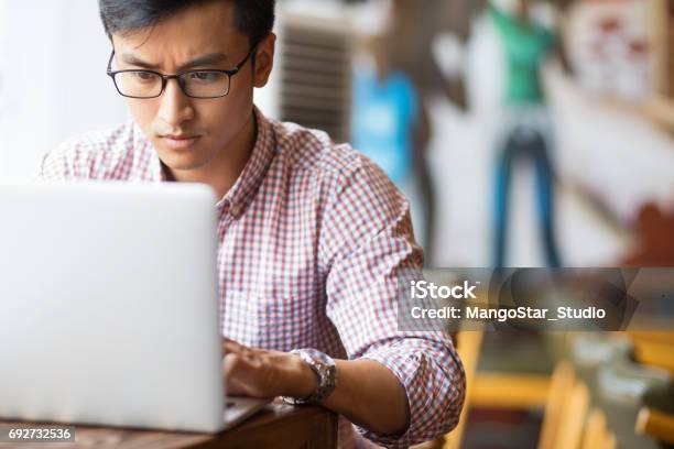 Serious Young Asian Student Using Laptop In Cafe Stock Photo - Download Image Now - Serious, Men, Typing