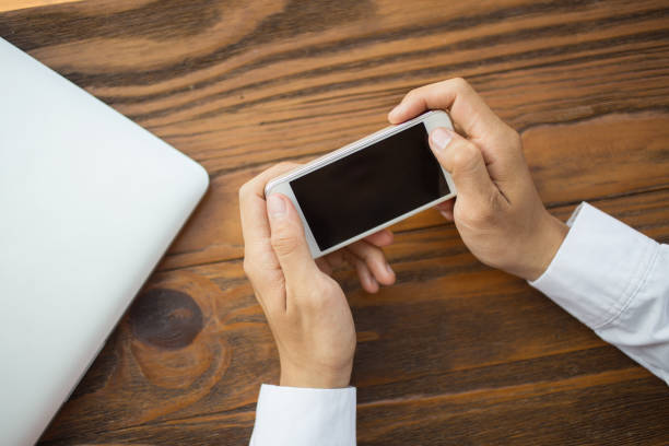 istock Close-up of male hands using smartphone at table 692732570