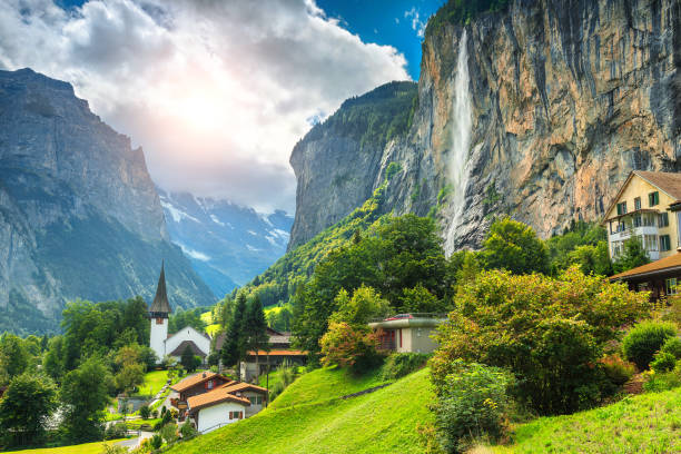 Fabulous mountain village with high cliffs and waterfalls, Lauterbrunnen, Switzerland Amazing touristic alpine village with famous church and Staubbach waterfall, Lauterbrunnen, Switzerland, Europe swtizerland stock pictures, royalty-free photos & images