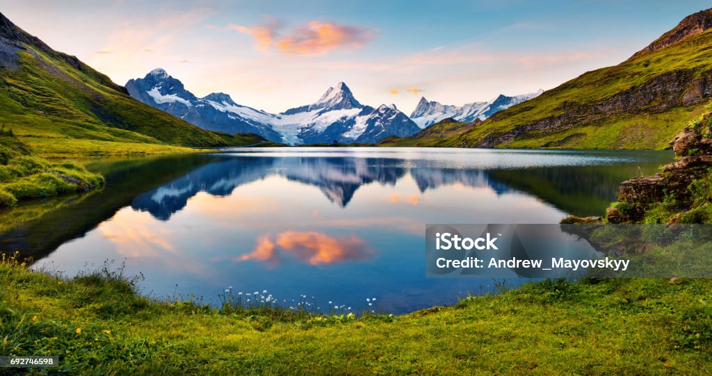 Wetterhorn and Wellhorn peaks reflected in water surface of Bachsee lake Wetterhorn and Wellhorn peaks reflected in water surface of Bachsee lake. Colorful summer sunrise in Bernese Oberland Alps, Grindelwald location, Innertkirchen, Switzerland, Europe. Switzerland Stock Photo