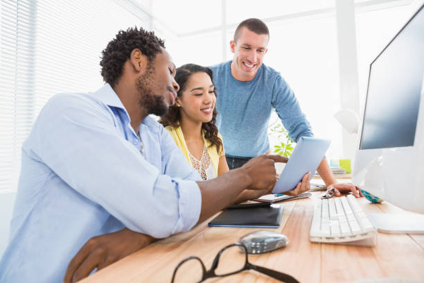 istock Smiling coworkers using tablet computer together and pointing the screen 692767662