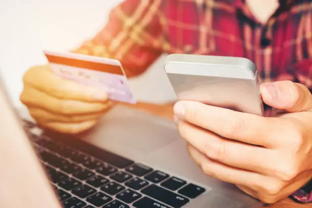 Photo of Man Holding Credit Card And Using Cell Phone holding credit card with shopping online