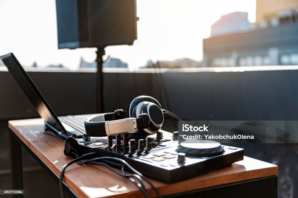 Contemporary technology for musical entertainment Modern music equipment with Dj mixer near laptop on table for party on roof. Large music column on background DJ Stock Photo