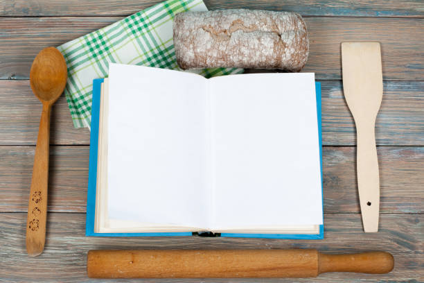 istock Open recipe book on wooden background, spoon, rolling pin , green checkered tablecloth 692772178