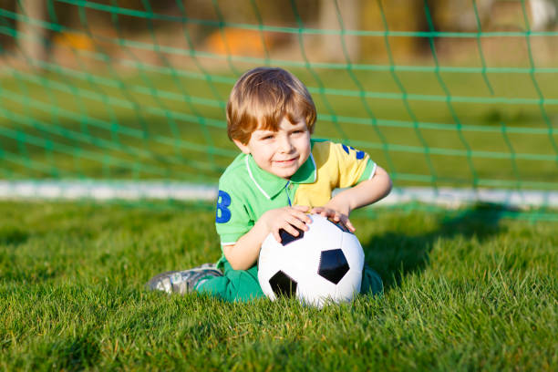 kleine süße kind junge von 4 spielen fußball mit fußball auf feld, im freien - playing field goalie soccer player little boys stock-fotos und bilder