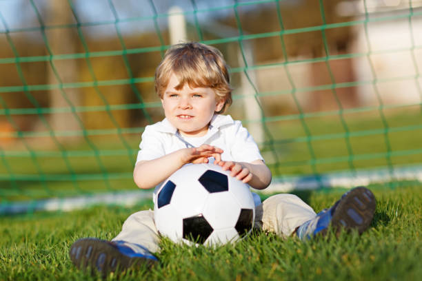 kleine süße kind junge von 4 spielen fußball mit fußball auf feld, im freien - playing field goalie soccer player little boys stock-fotos und bilder