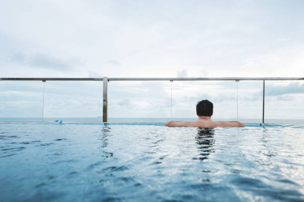 istock a man relaxing in swimming pool, with blue sky background 692775760