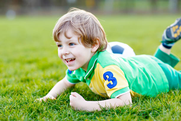 kleine süße kind junge von 4 spielen fußball mit fußball auf feld, im freien - playing field goalie soccer player little boys stock-fotos und bilder