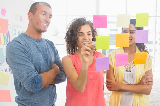 istock Smiling coworkers writing on sticky notes 692786638