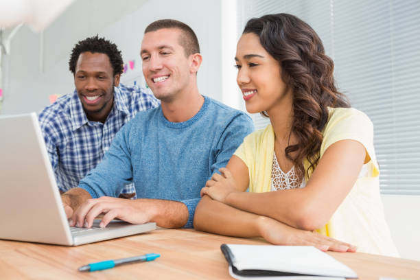 istock Smiling colleagues working together with laptop 692790910