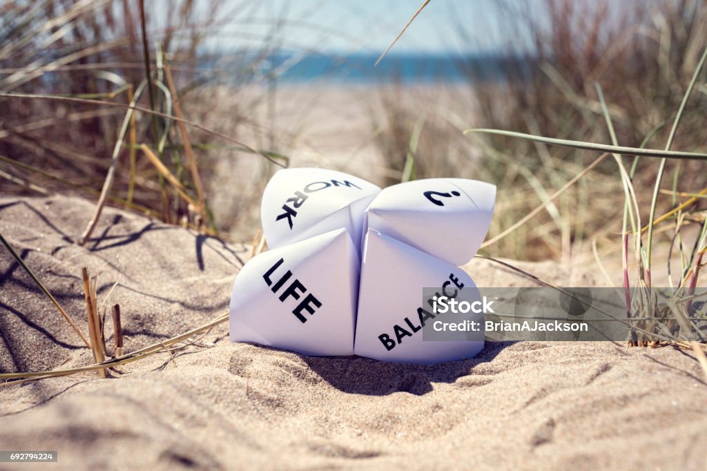 Work life balance choices Origami fortune teller on vacation at the beach concept for work life balance choices Working Stock Photo
