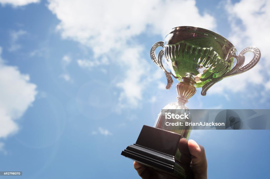 Holding up a trophy cup as a winner Celebrating with trophy award for success or first place sporting championship win Trophy - Award Stock Photo