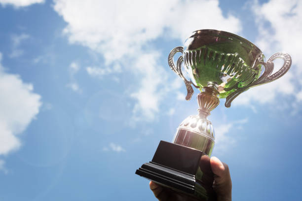 Holding up a trophy cup as a winner Celebrating with trophy award for success or first place sporting championship win winners podium photos stock pictures, royalty-free photos & images