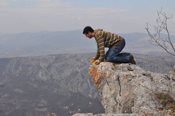 young man going on a cliff edge  on the top of mountain with gorgeous view. - high up imagens e fotografias de stock