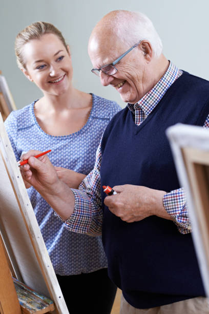 istock Senior Man Attending Painting Class With Teacher 692801930