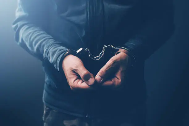 Photo of Arrested computer hacker and cyber criminal with handcuffs