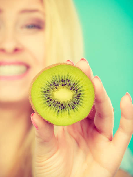 istock Woman holding green kiwi fruit 692806306
