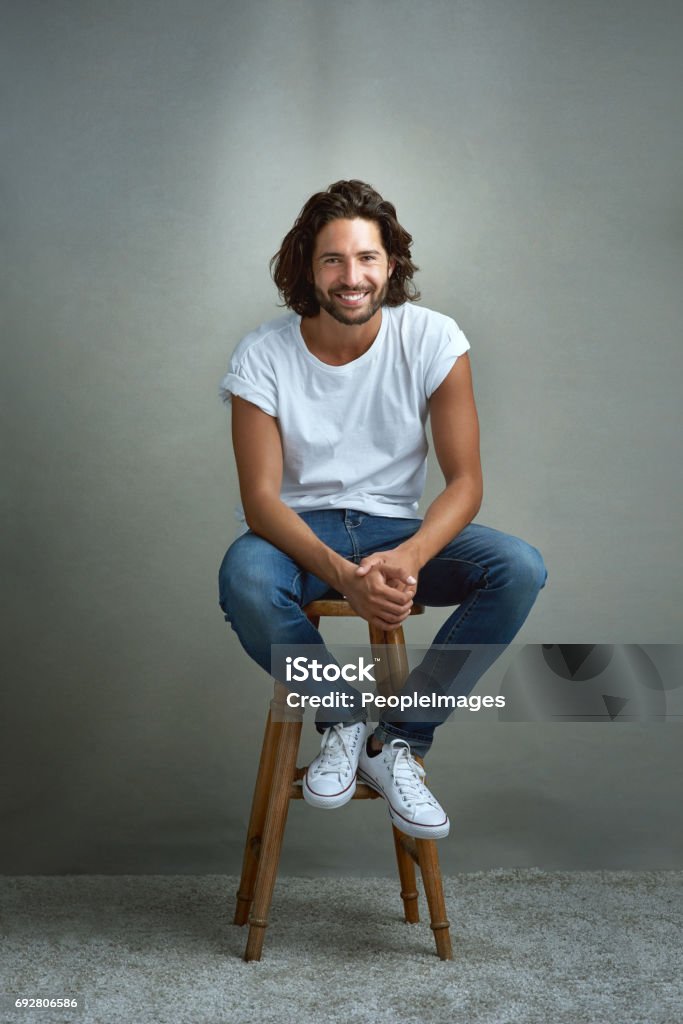 I'm just an easygoing kinda guy Studio portrait of a handsome young man posing against a grey background Men Stock Photo