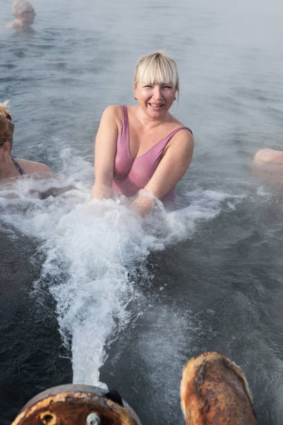 Smiling woman take a therapeutic (medicinal) baths in pool with natural thermal mineral water in winter season Anavgay Village, Kamchatka Peninsula, Russian Far East - February 2, 2013: Smiling woman take a therapeutic (medicinal) baths in public pool with natural thermal mineral water having balneological properties in winter season. geothermal reserve stock pictures, royalty-free photos & images