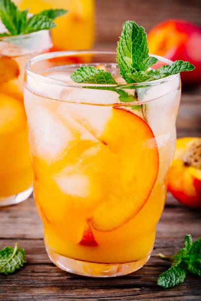 istock Summer cold drinks: homemade peach ice tea with ice cubes, and mint in glasses 692814290