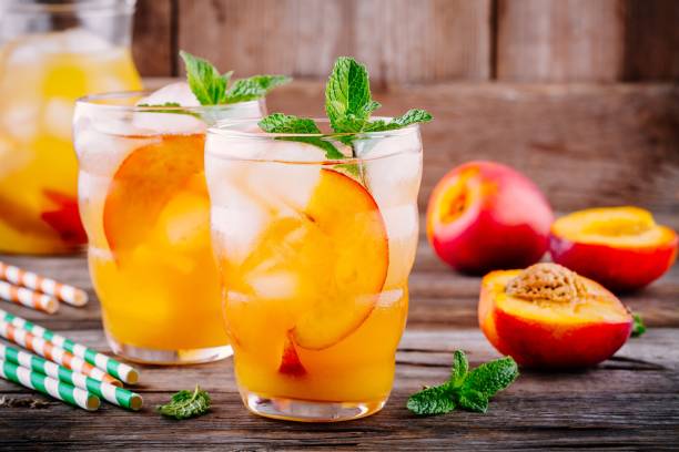 bevande fredde estive: limonata di pesca fatta in casa con cubetti di ghiaccio e menta in bicchieri - peach nectarine wet drop foto e immagini stock