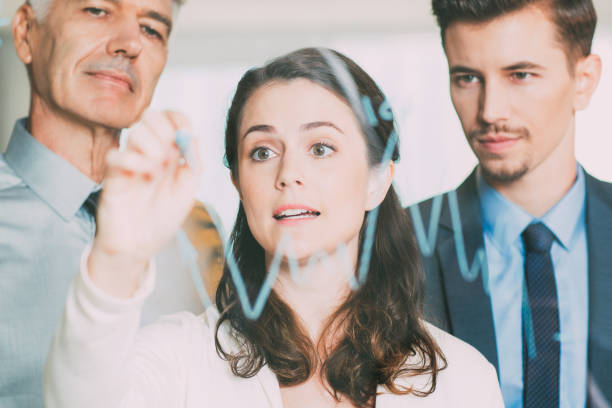 istock Young Businesswoman Drawing Graph with Colleagues 692818772