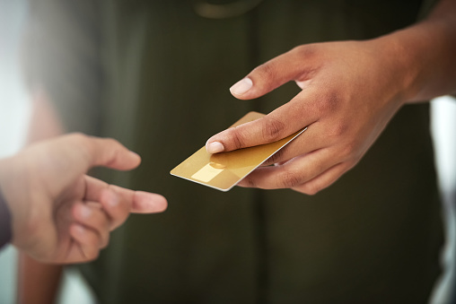 Cropped shot of an unrecognisable person handing over a credit card for payment