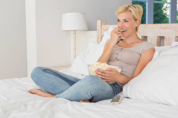 istock Smiling blonde woman eating pop corn 692826910