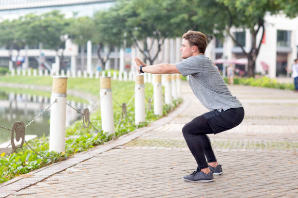 istock Serious Sporty Man Doing Squats Outdoors 692827828