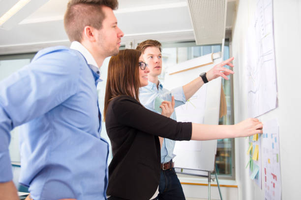 istock Business People Discussing Over Line Graph Stuck On Wall 692832474