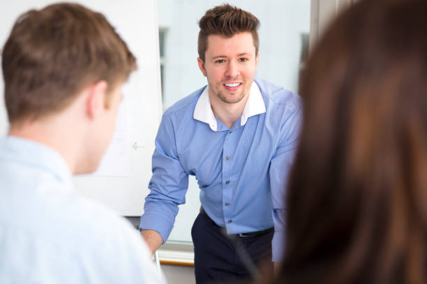 istock Businessman Smiling While Looking At Colleagues In Office 692832896