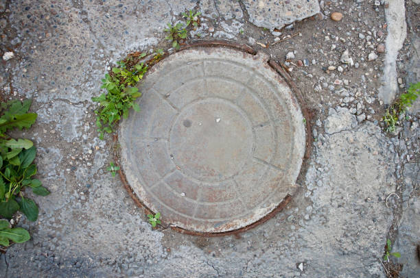 Old metal manhole. Closeup. The view from the top Old metal manhole. Closeup. The view from the top. sewer lid stock pictures, royalty-free photos & images