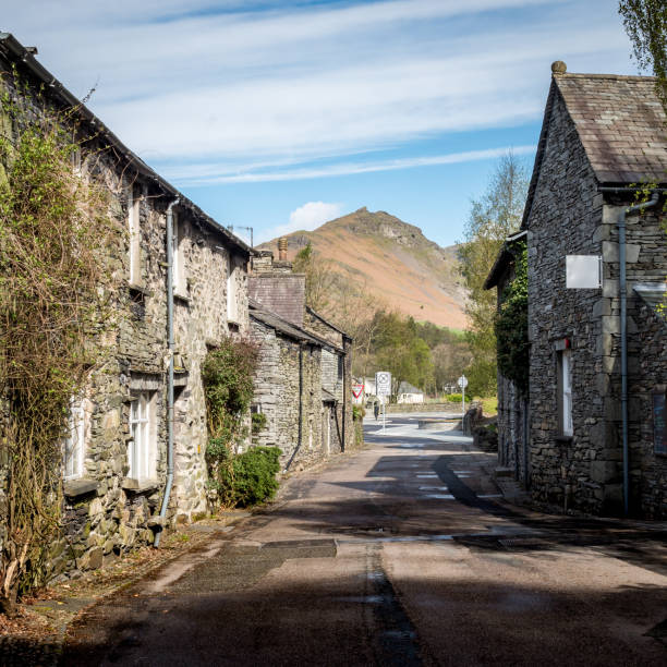 Grasmere, Lake District, Cumbria, England Traditional cottages on a quiet road in the the quaint English Lake District town of Grasmere on a bright spring morning. grasmere stock pictures, royalty-free photos & images