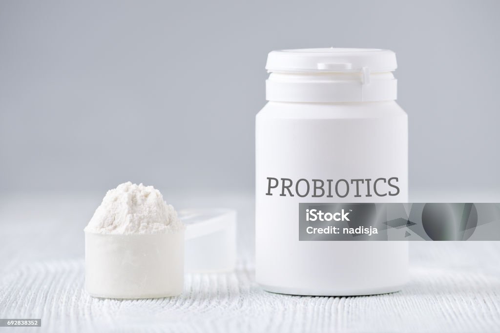 a jar and spoon with probiotic powder on gray a white jar and spoon with probiotic powder on gray background Probiotic Stock Photo