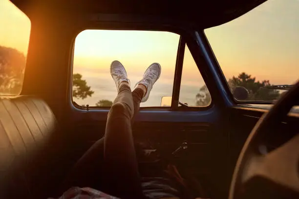 Cropped shot of an unrecognizable woman lying in a car during a roadtrip