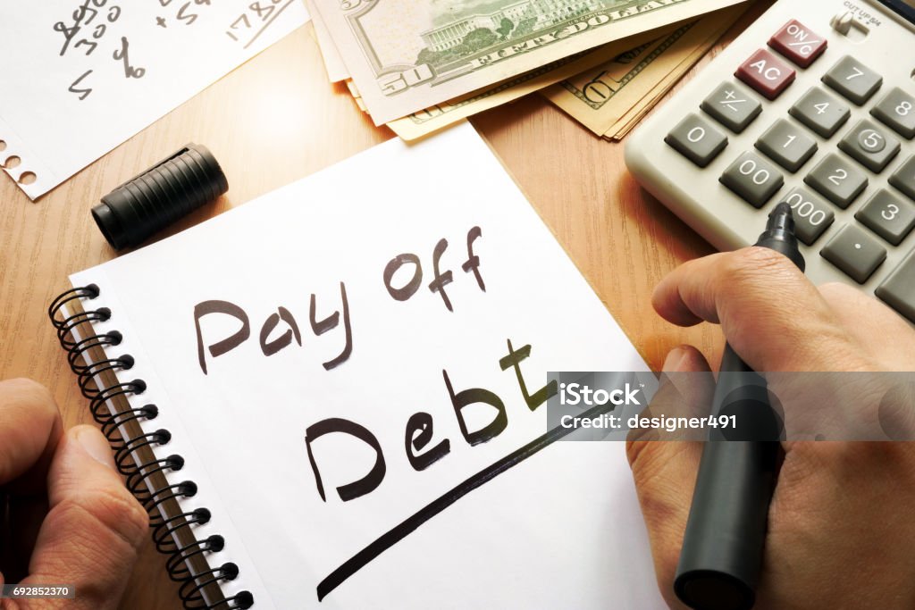 Note with words pay off debt concept. Debt Stock Photo