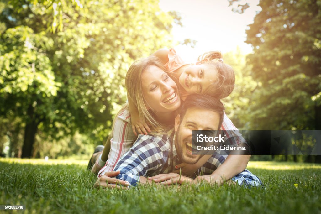 幸せな家族を楽しんで一緒に夏の日。家族は、草の上に横たわる。母と父の上に横たわる娘便乗します。 - 家族のロイヤリティフリーストックフォト