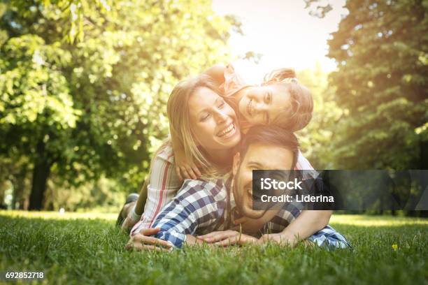 幸せな家族を楽しんで一緒に夏の日家族は草の上に横たわる母と父の上に横たわる娘便乗します - 家族のストックフォトや画像を多数ご用意 - 家族, 春, 自然