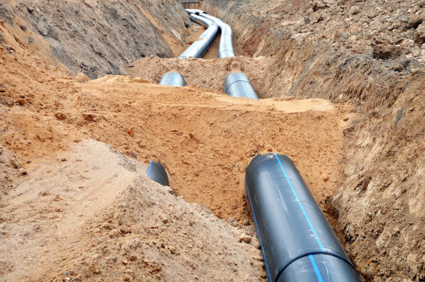 The process of laying of engineering and heating systems. The process of laying of engineering and heating systems. Two black plastic pipes are in a trench of sand in perspective. trench stock pictures, royalty-free photos & images