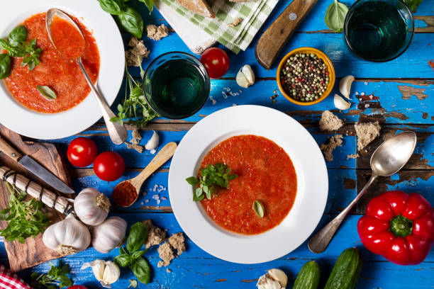 istock Tasty appetizing classic spanish soup gazpacho in white plates on rustic blue table with bread, garlic and spices. Dinner Food Concept. Top View. 692856082