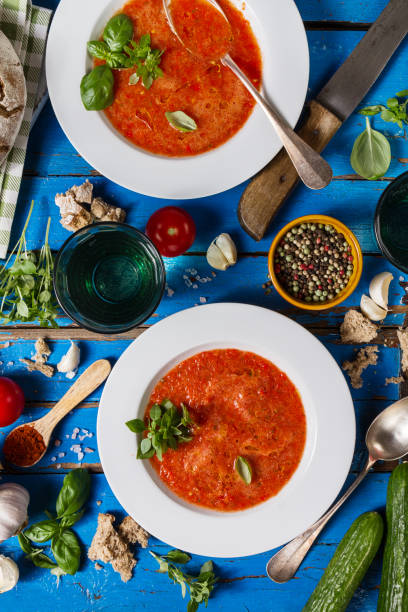 istock Tasty appetizing classic spanish soup gazpacho in white plates on rustic blue table with bread, garlic and spices. Dinner Food Concept. Top View. 692856184